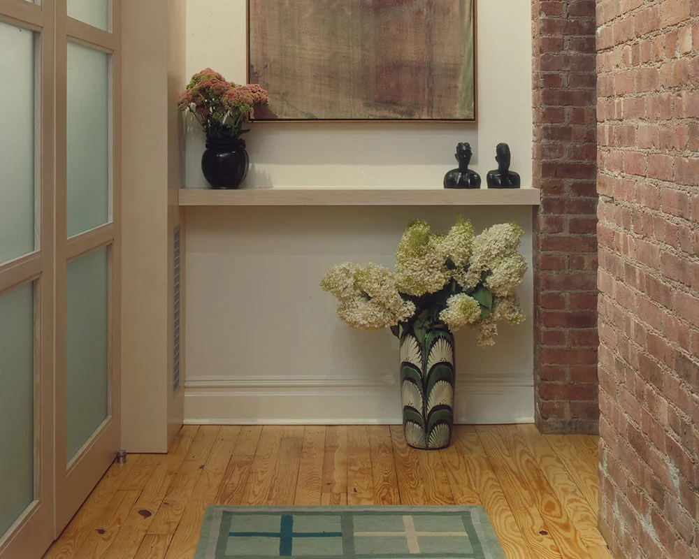 A vase of flowers in the middle of a hallway.