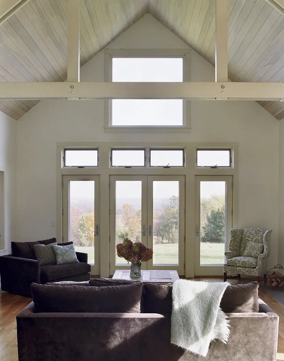 A living room with two large windows and couches.