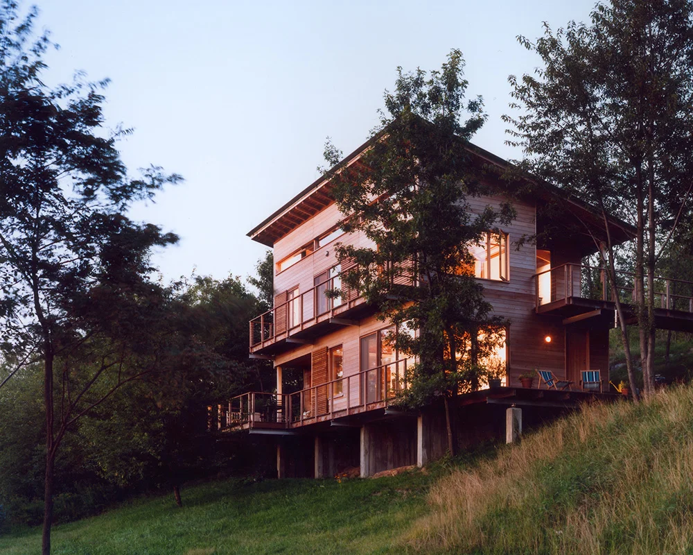 A house sitting on top of a hill with trees in the background.